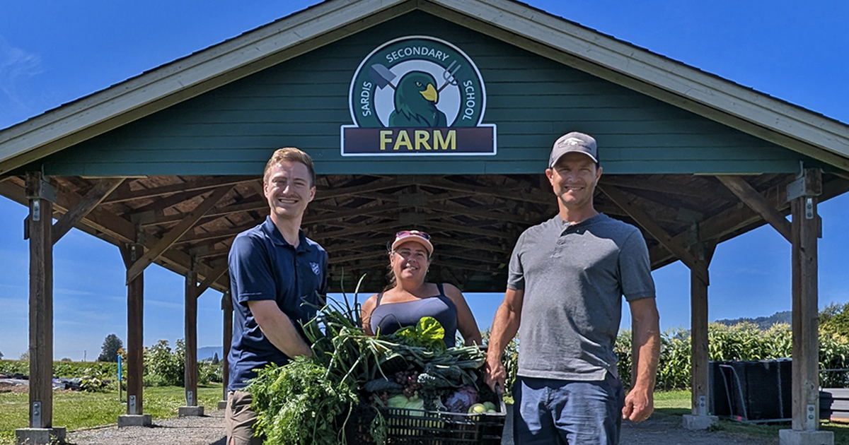 Three people hold up produce