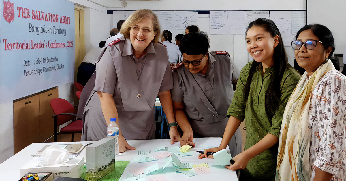 A group of four women standing by a table