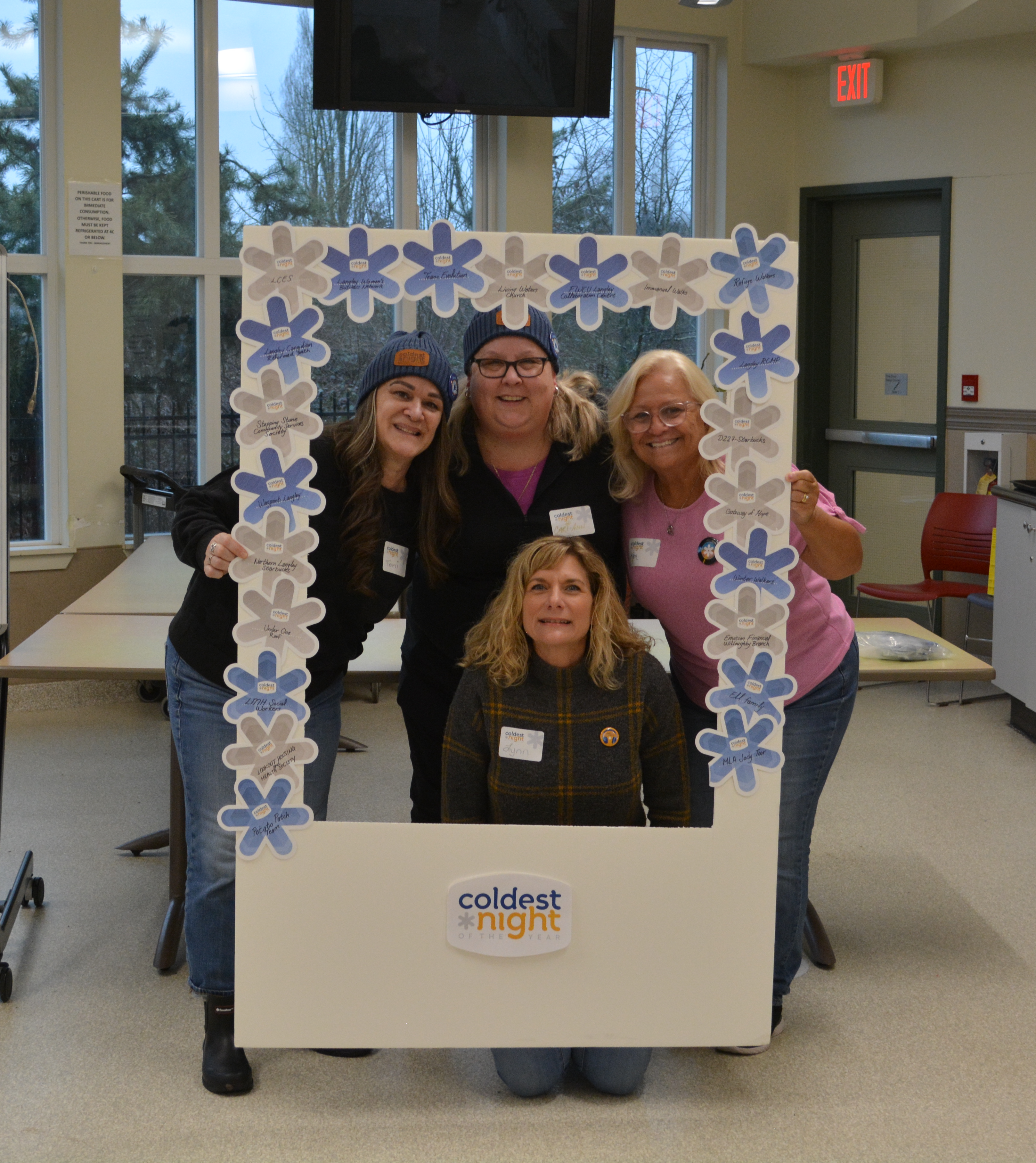 Four volunteers holding up a large polaroid frame that is CNOY themed. 